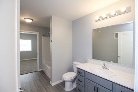 A bathroom with a toilet, sink, and mirror.