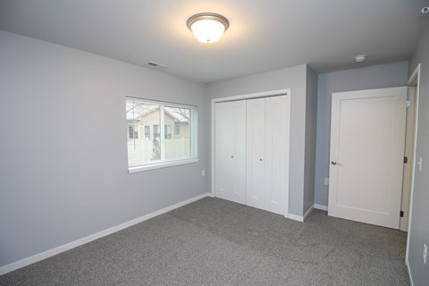 A room with a carpeted floor and a window showing a house outside.