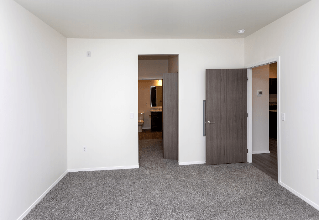 a living room with white walls and a door to a bedroom