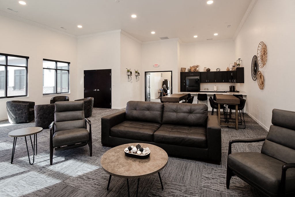 A living room with black furniture and a grey carpet.