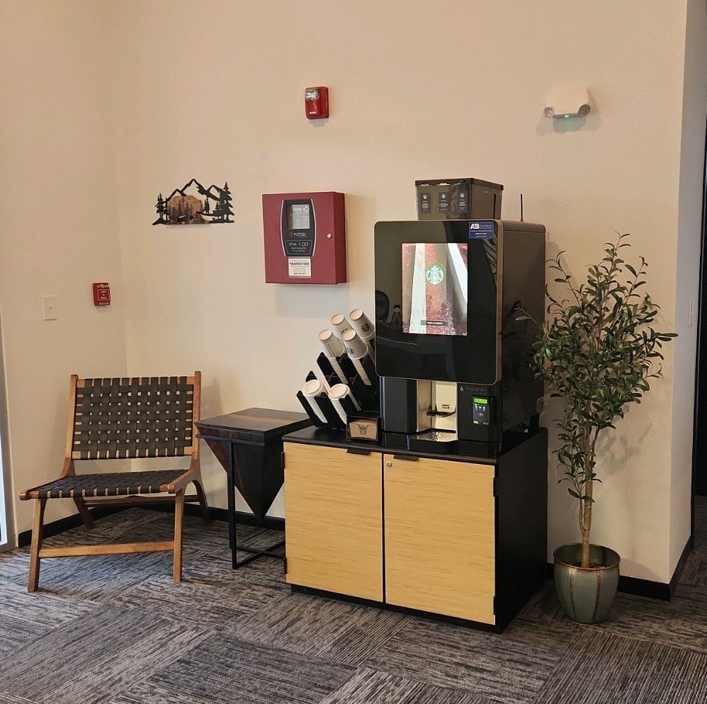 A wooden chair sits in front of a coffee machine and a vending machine.