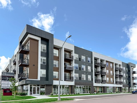 The Crimson apartment building is a modern, multi-story structure with balconies and large windows.