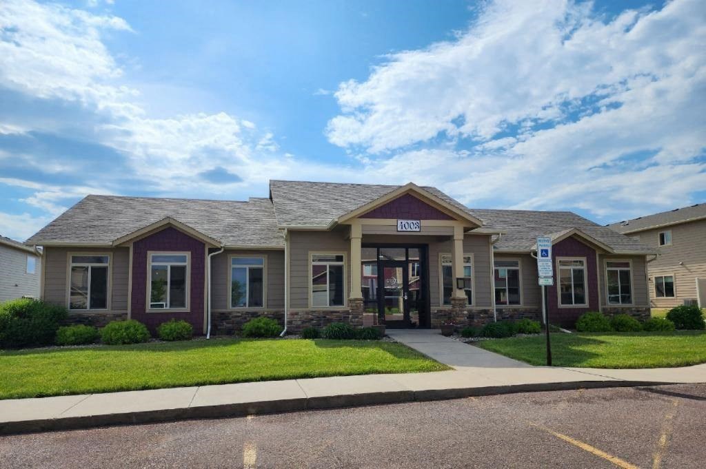 the front of a building with a sidewalk and grass
