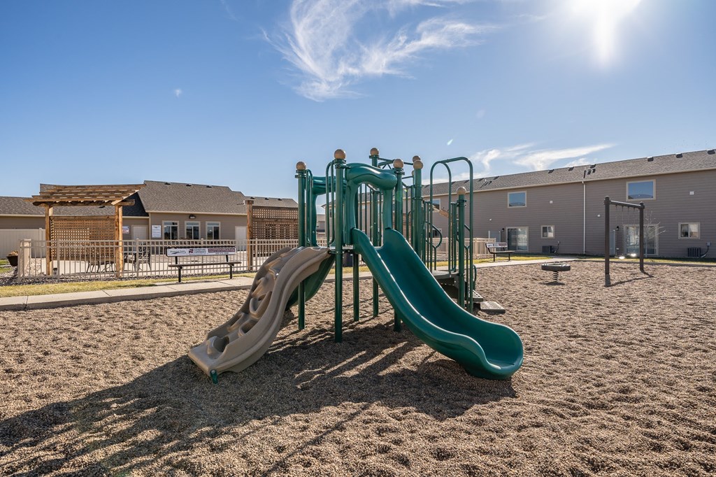 a playground with slides and sand in front of a building