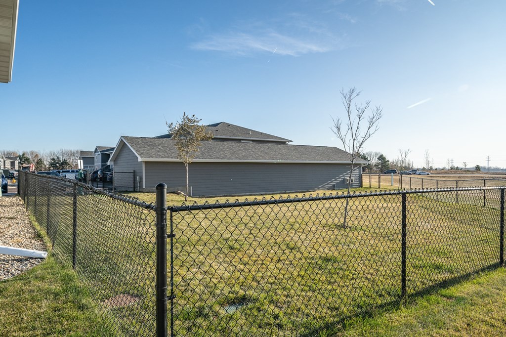 a house behind a chain link fence in front of a field