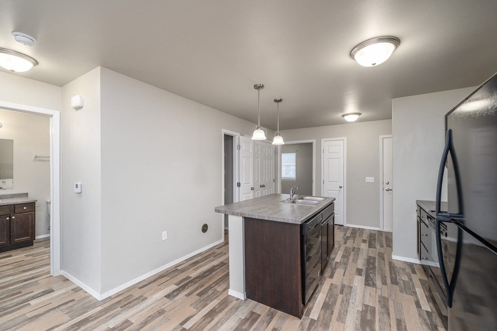 a kitchen with an island and a refrigerator and a door to a hallway