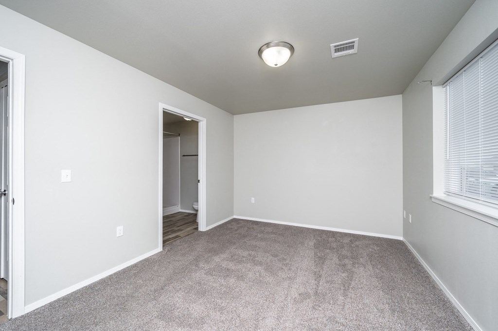an empty living room with carpet and a door to a hallway