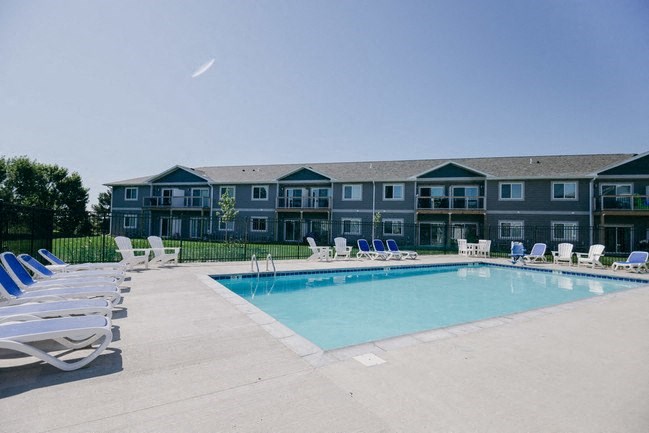 a swimming pool with chairs and a building in the background