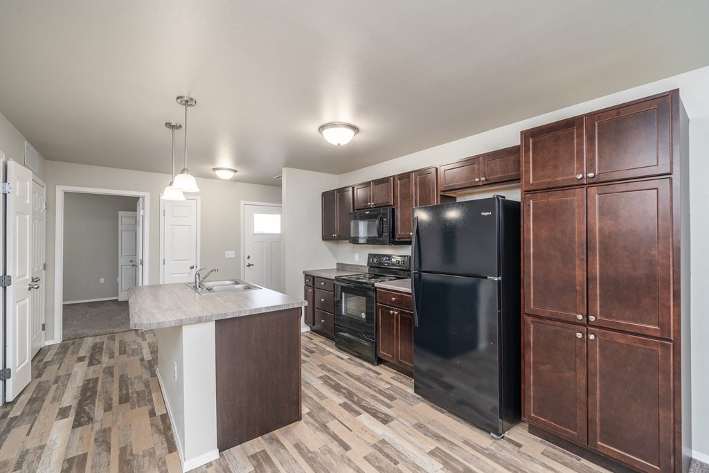 a kitchen with wooden cabinets and a black refrigerator