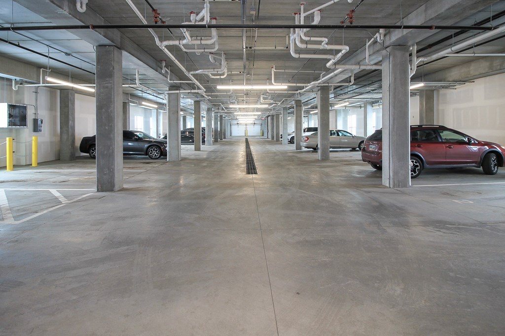A parking garage with cars parked on both sides of the aisle.