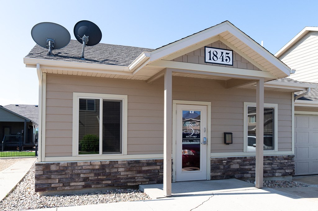 the front entrance of a tan building with two satellite dishes on the roof