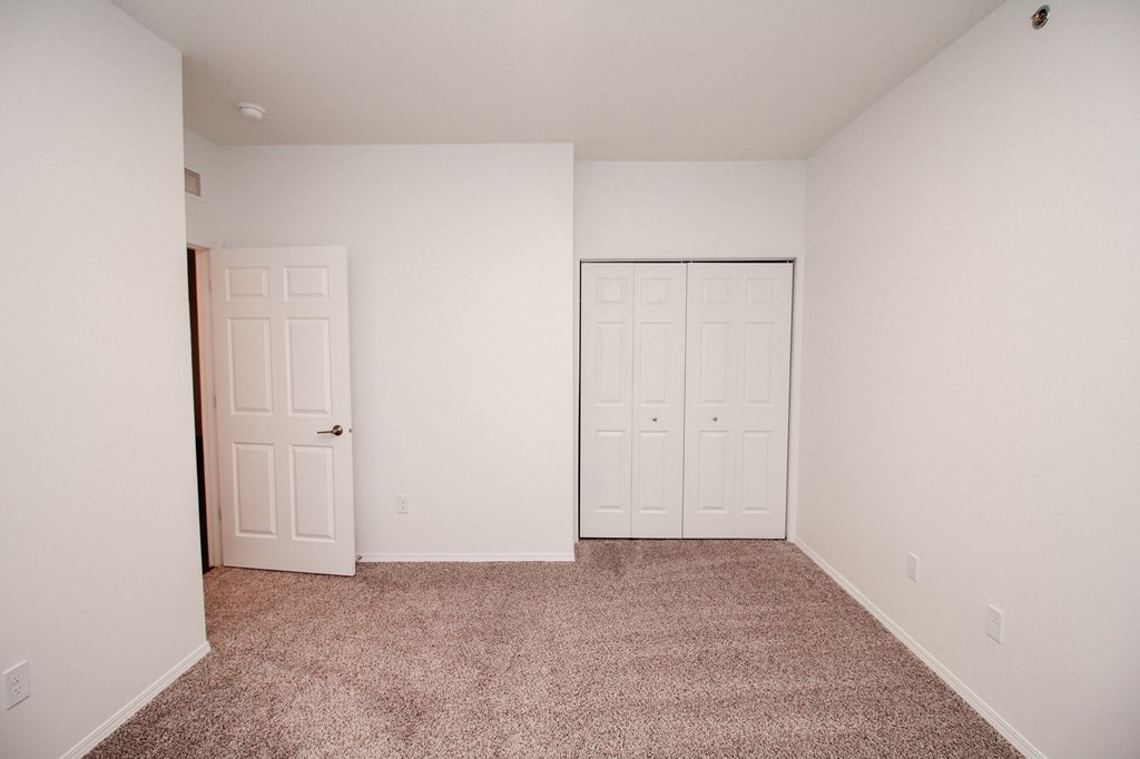 A bedroom with a carpeted floor and two doors.