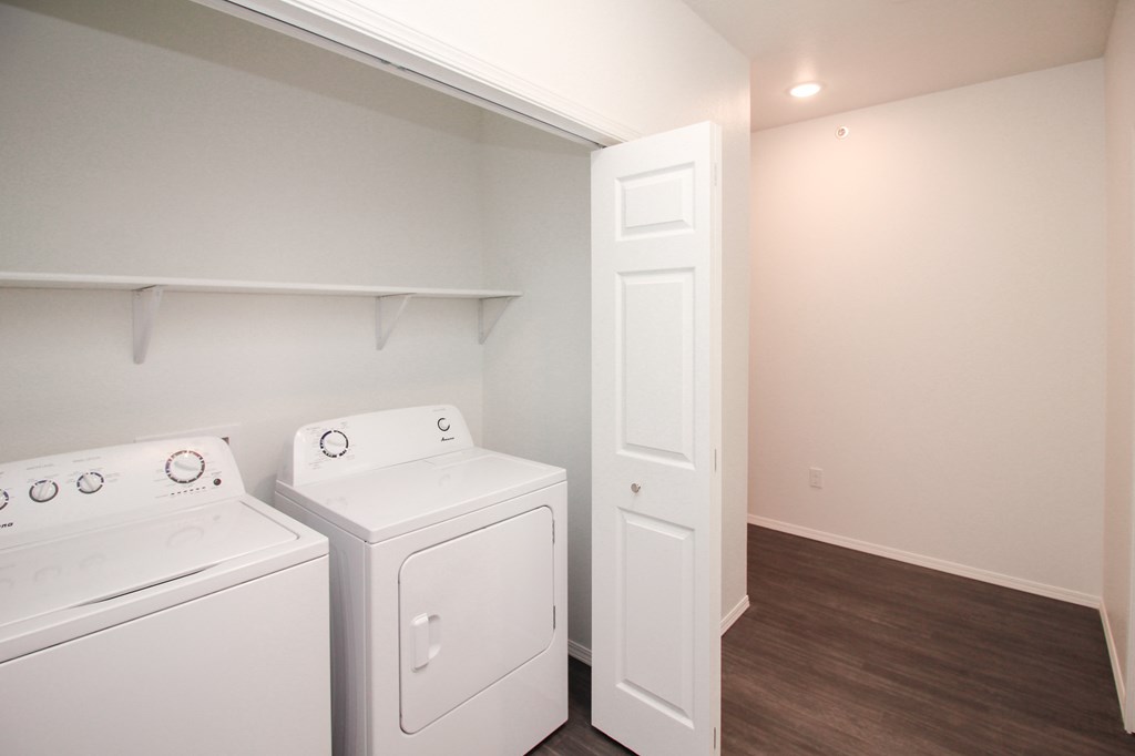 Two white front loading washing machines in a laundry room.