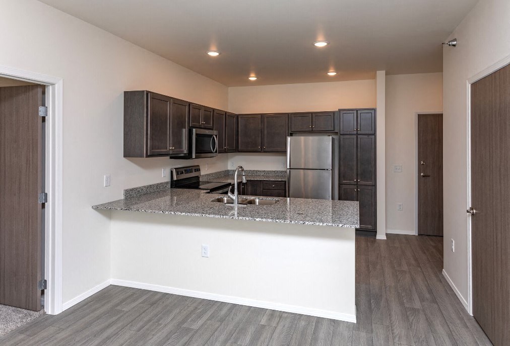 a kitchen with a granite counter top and a stainless steel refrigerator