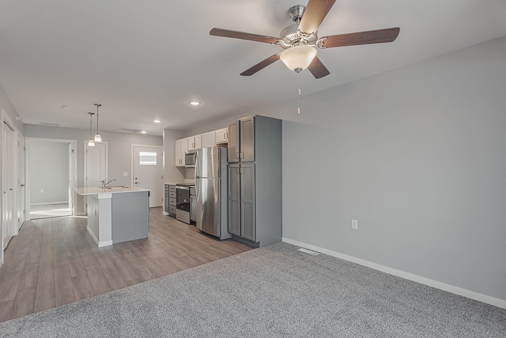 a living room with a ceiling fan and a kitchen