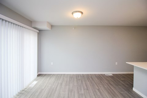 A room with a wooden floor and a window with white blinds.