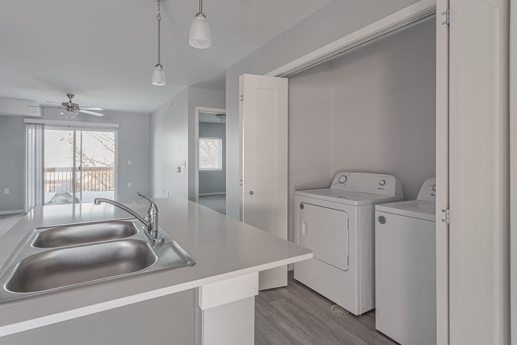 a kitchen with a sink and a washer and dryer and a laundry room