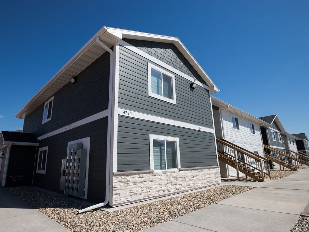 a gray house with a stone facade and a sidewalk