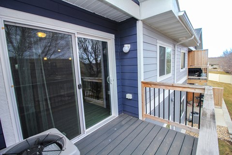 A blue house with a deck and sliding glass doors.