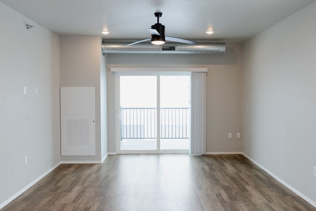 an empty living room with a sliding glass door and a ceiling fan