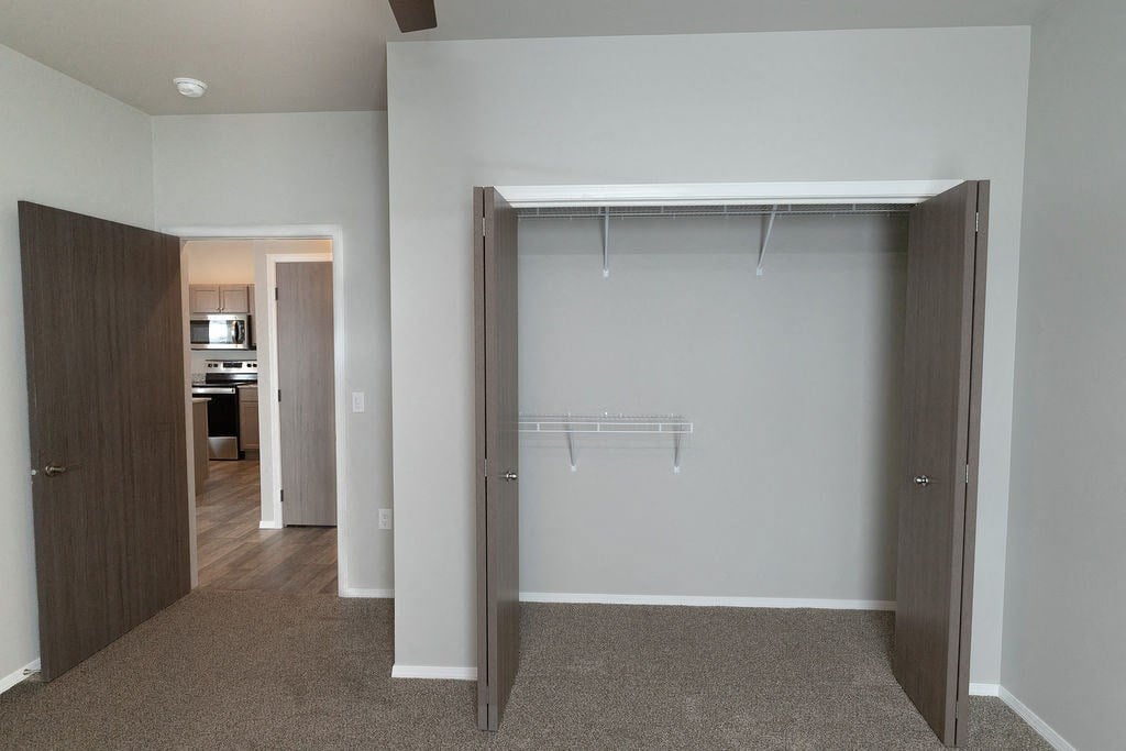 a walk in closet in an empty room with a door open