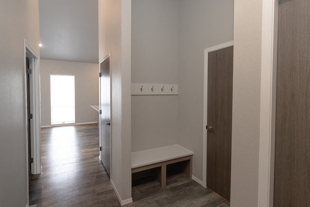 a room with a bench and a hallway with a door