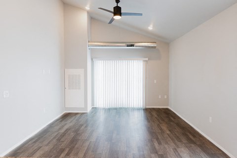 an empty living room with a ceiling fan and a window