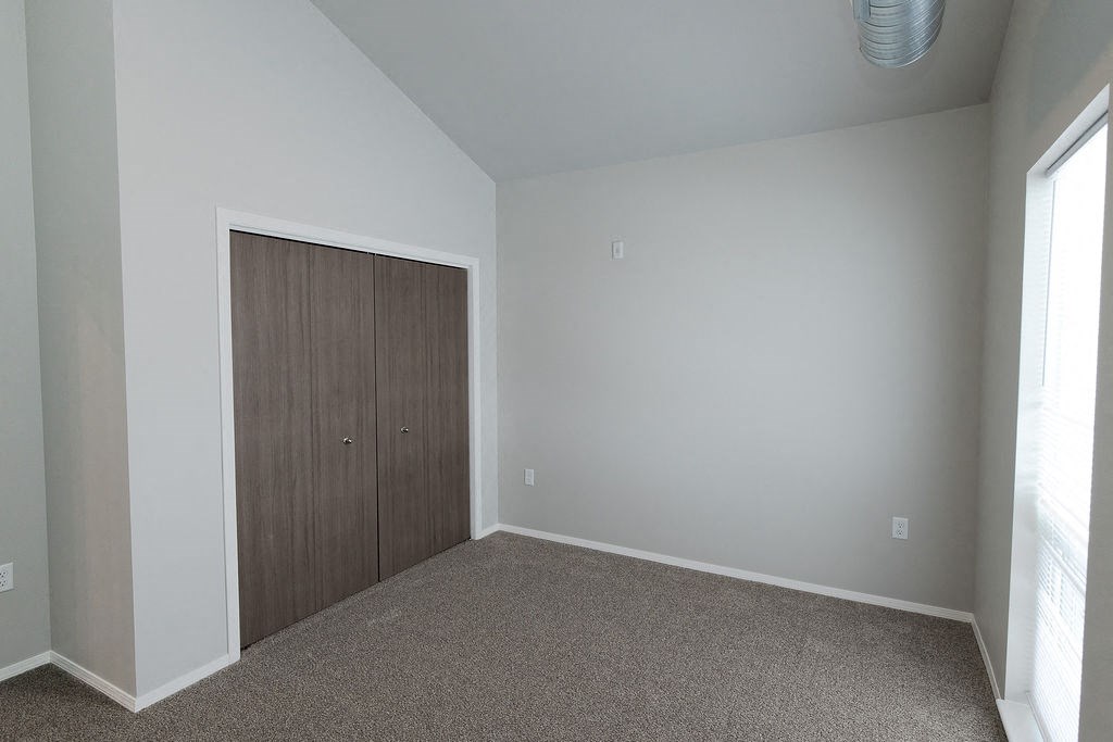 a bedroom with a closet and a carpeted floor