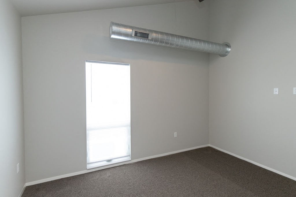 an empty room with a window and a pipe on the wall
