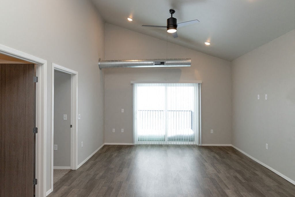 an empty living room with a window and a ceiling fan