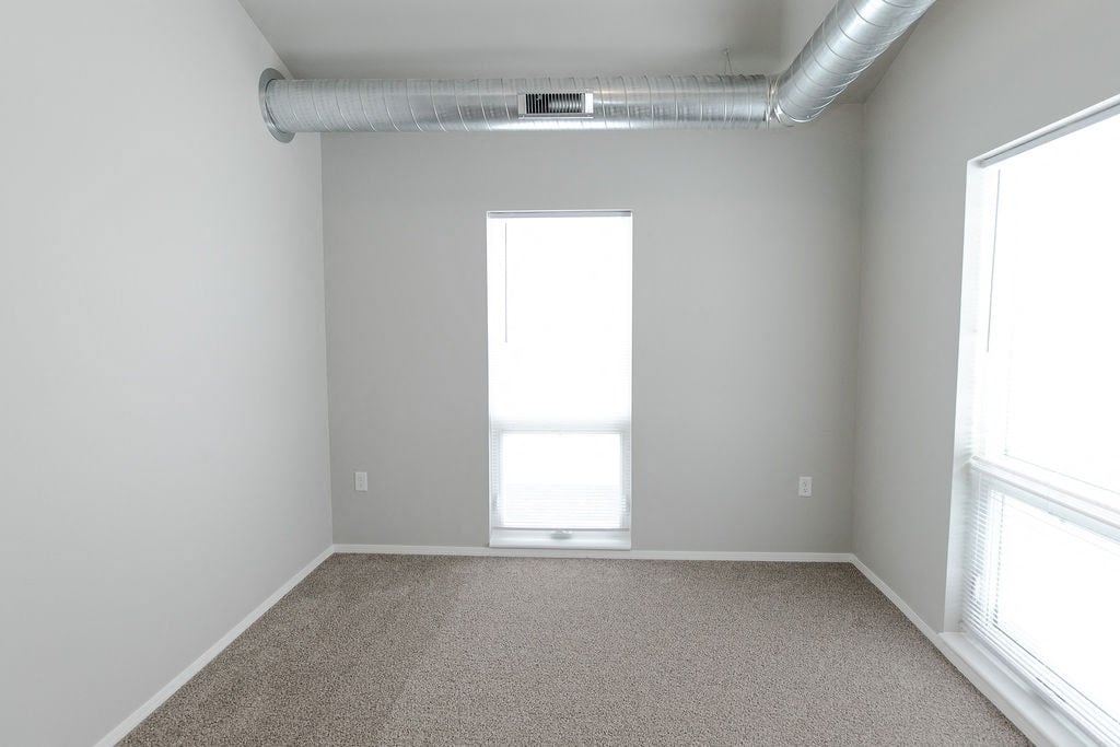 an empty room with a window and a carpet