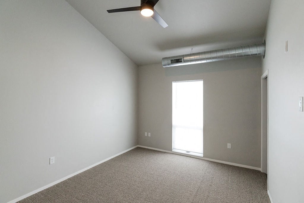 an empty room with a window and a ceiling fan