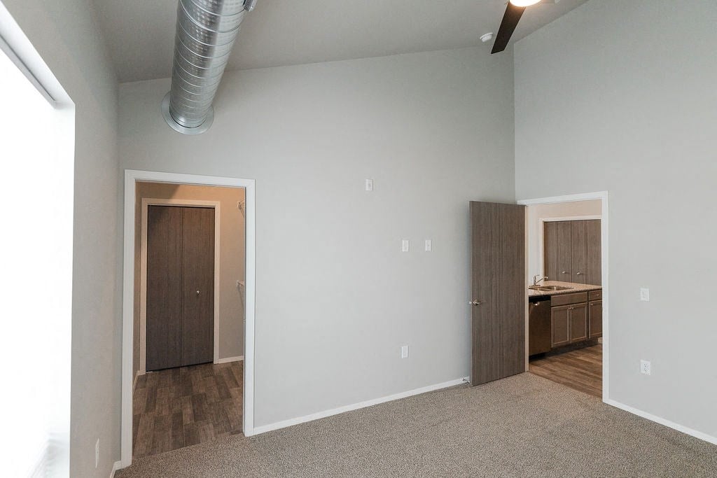 a bedroom with a door to a bathroom and a kitchen