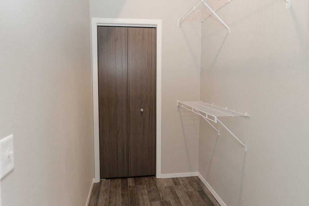a closet in a small room with a wooden door and a hanging rack