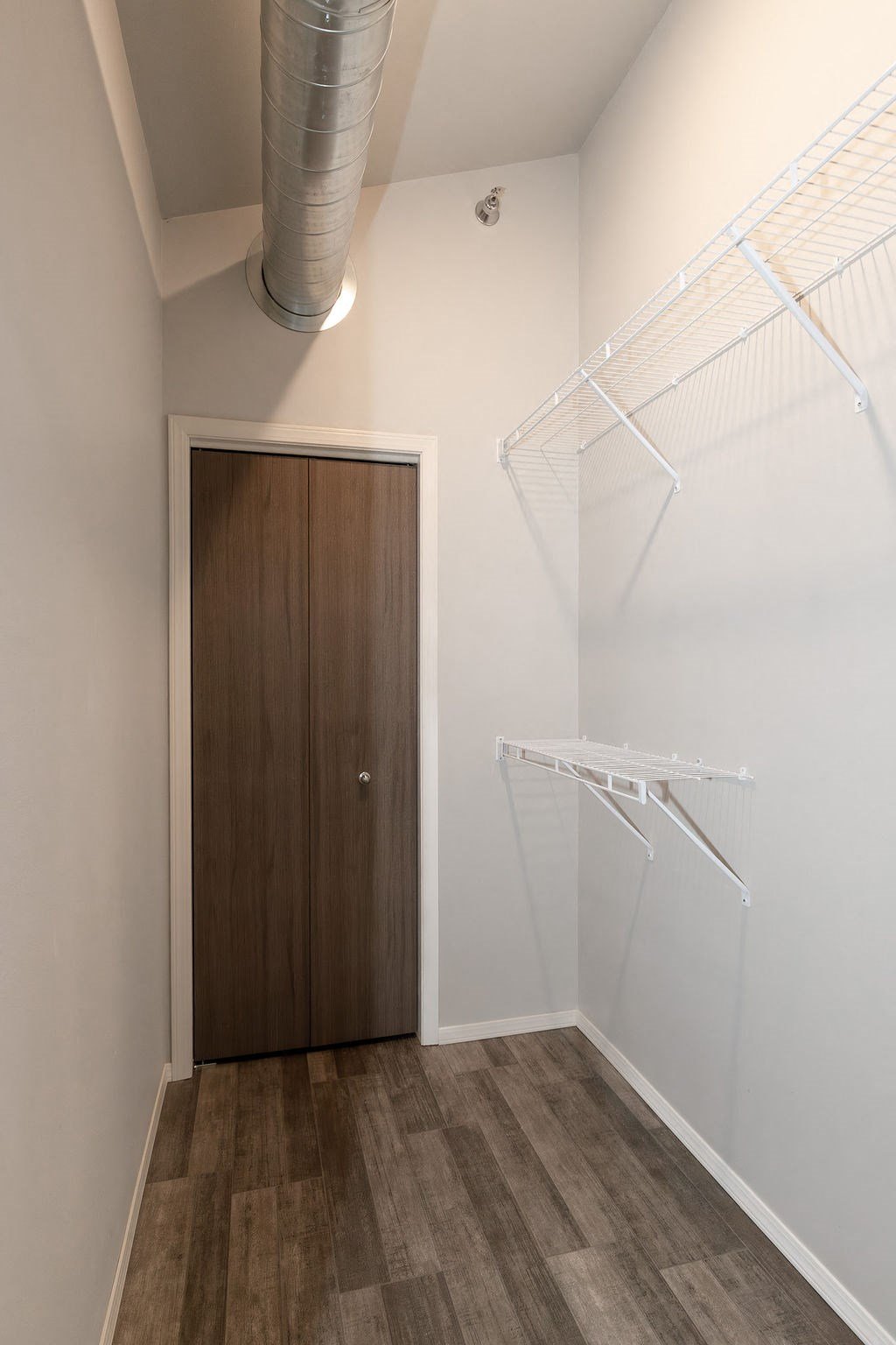 a closet in a white room with a wooden door