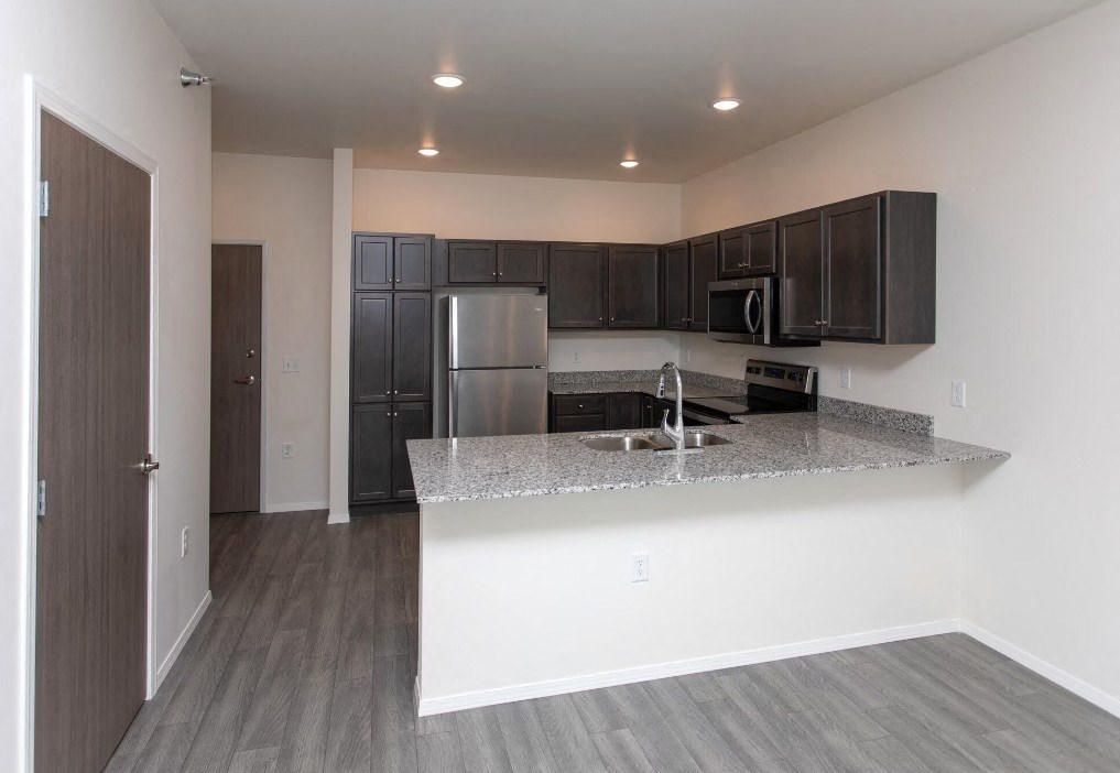 a kitchen with a granite counter top and a stainless steel refrigerator