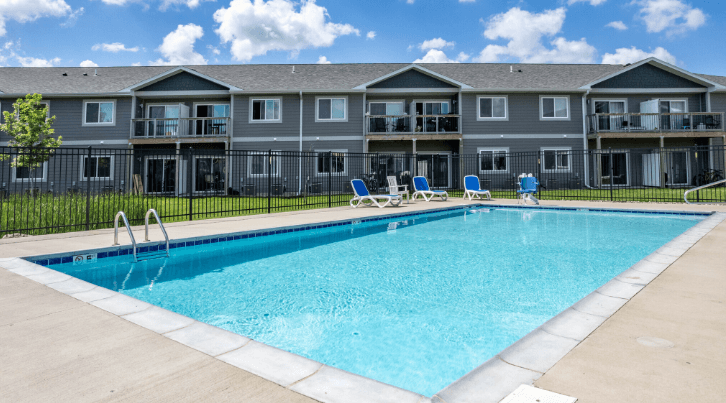 A large swimming pool in front of apartment buildings.