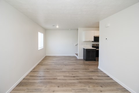 A spacious room with wooden flooring and white walls.