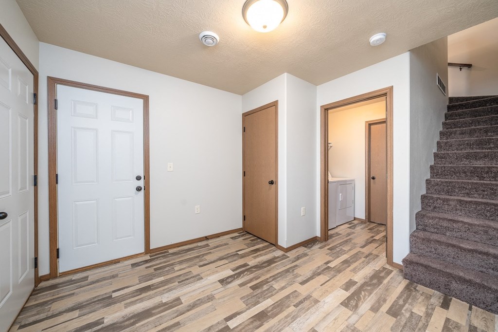 an empty living room with a staircase and two doors