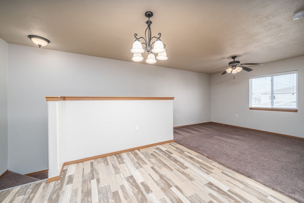 the living room and dining room of an empty home with a ceiling fan