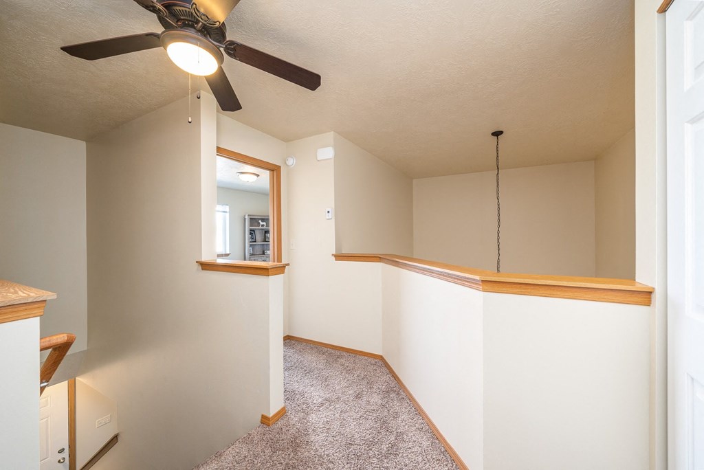 an empty living room with a ceiling fan and white walls
