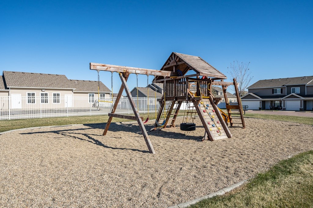 a swing set in a playground with a house in the background