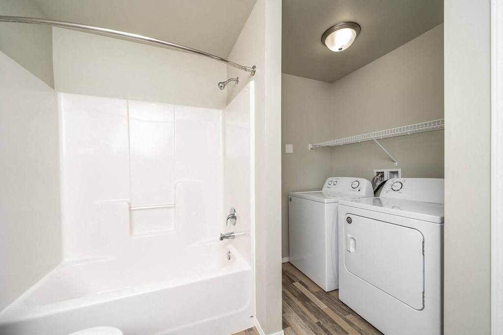 a white washer and dryer in a laundry room next to a white tub
