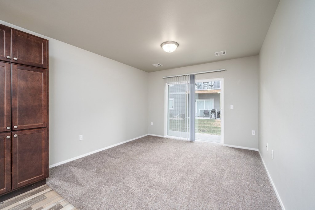 an empty living room with a large window and a door to a balcony