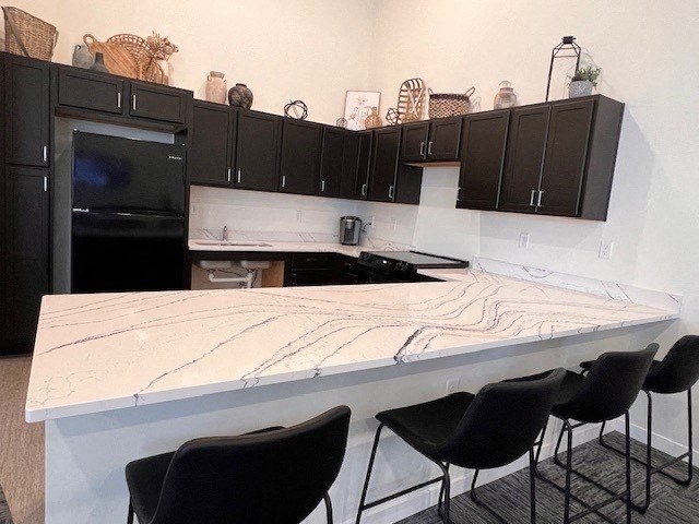 a kitchen with black cabinets and a marble counter top