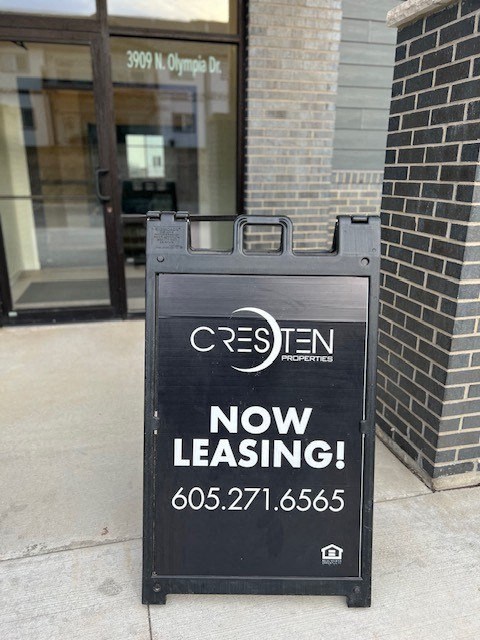 a now leasing sign on the sidewalk in front of a building