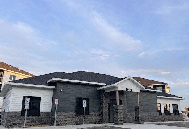 a gray building with a black roof on a street