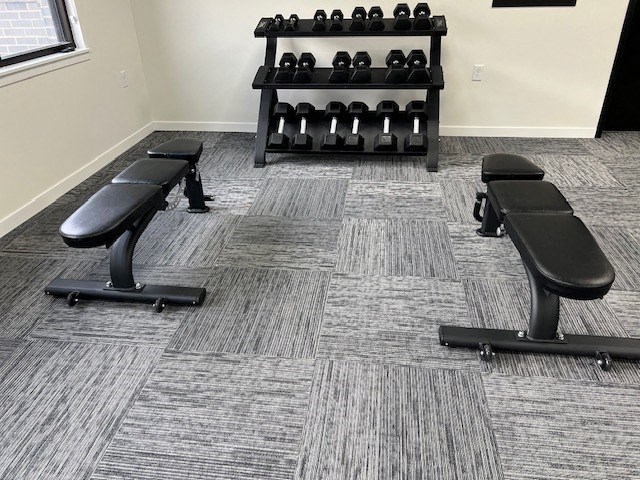 a gym with three chairs and a rack of dumbbells