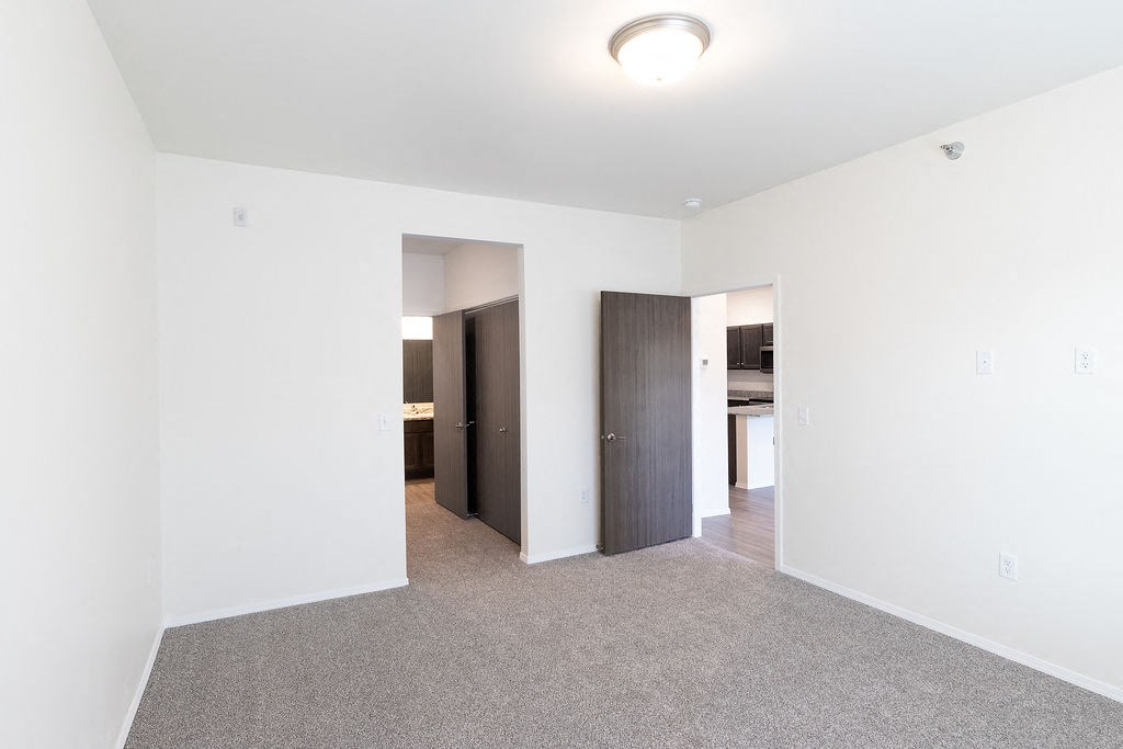 an empty living room with white walls and a door to a bathroom