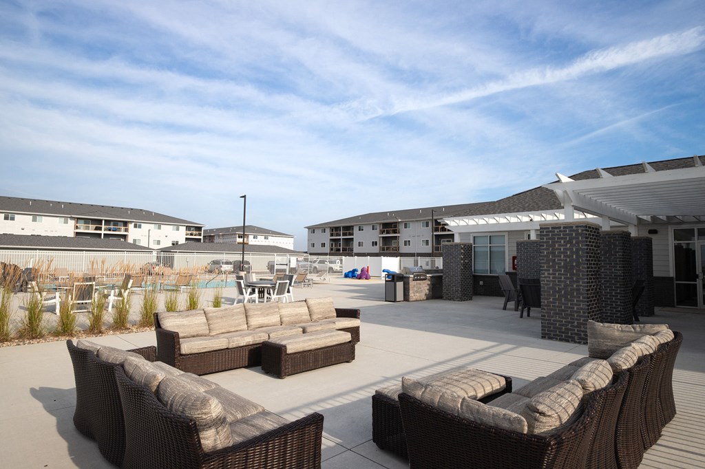 a patio with couches and chairs and a pool in the background